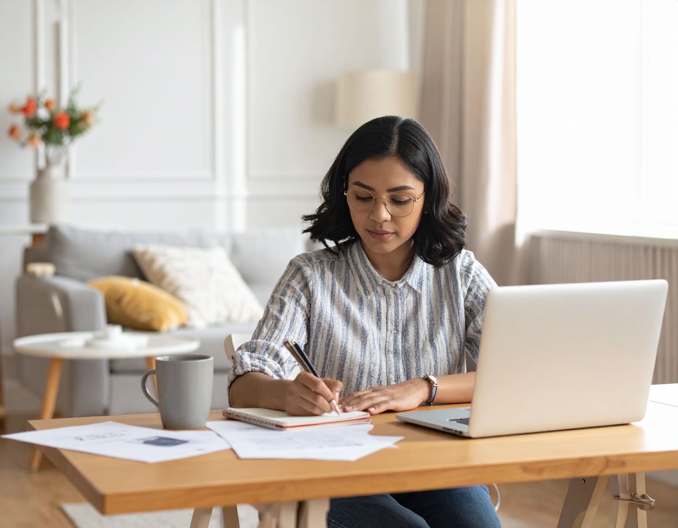 Young junior doctor at a desk, making notes and reviewing application materials while preparing for consultant interviews and aligning their experience with NHS Trust priorities.