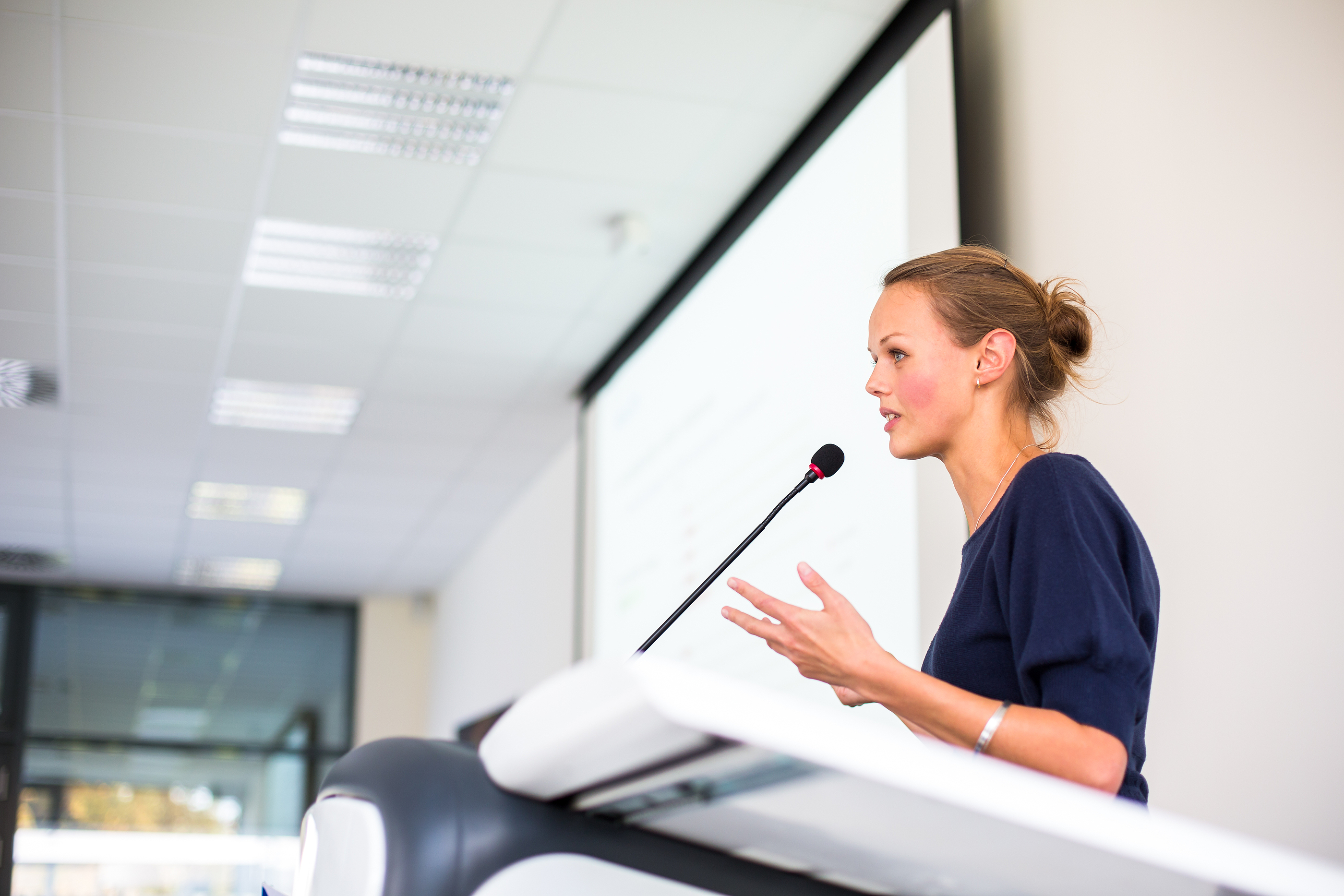 Junior doctor giving a consultant interview presentation, speaking confidently to the panel.