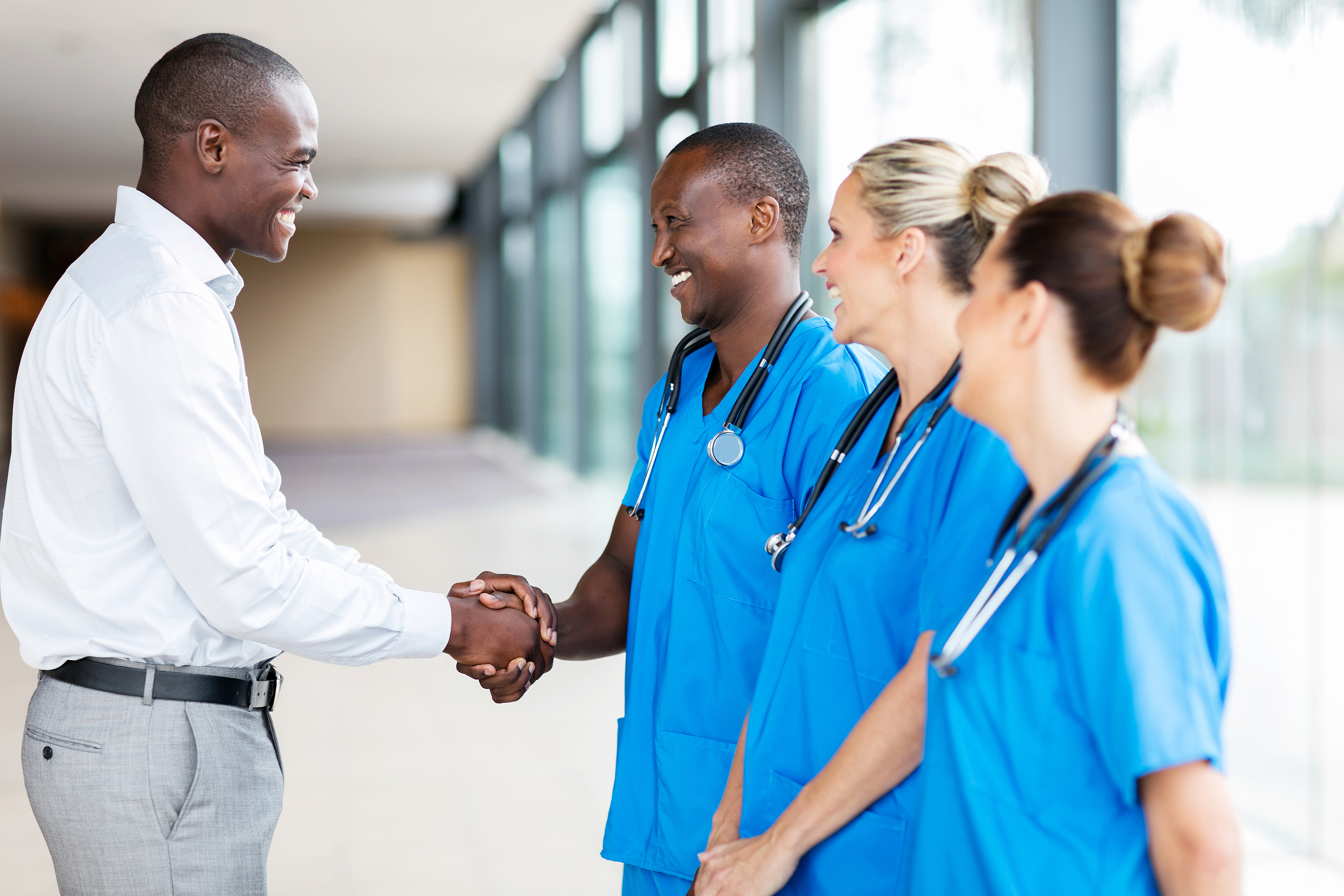Medical professional shaking hands during a pre-interview visit, representing the importance of making a positive impression before NHS consultant interviews.